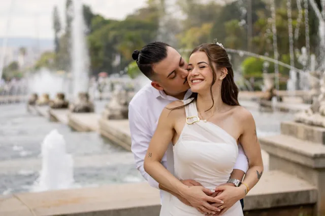 Noivo beijando o rosto da noiva diante de um chafariz em ensaio pré-wedding