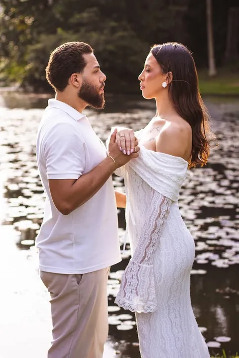 Casal de mãos dadas à beira de um lago durante ensaio pré-wedding